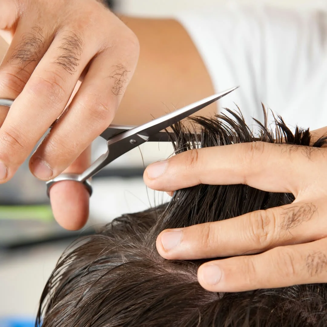 A person getting a haircut with scissors by a hairstylist.