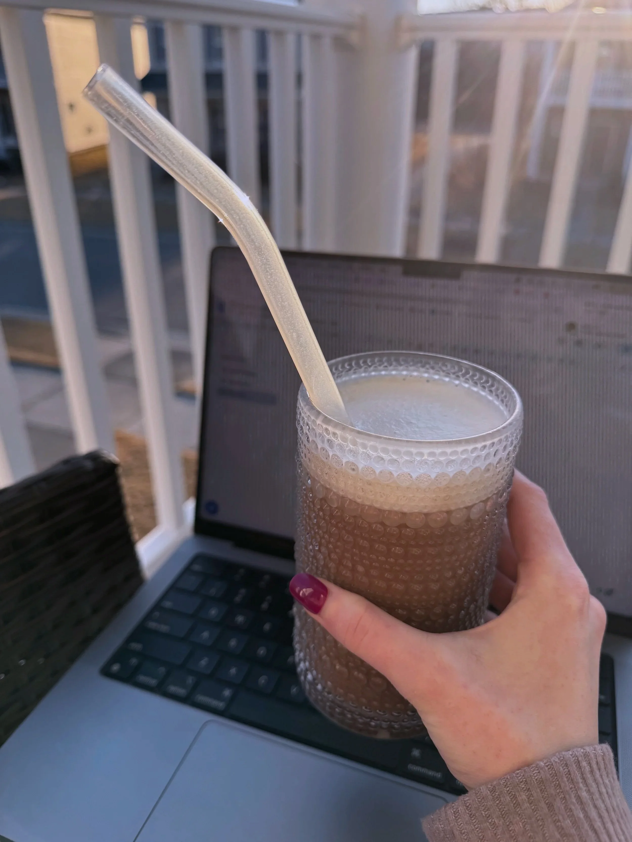 girl with pink nails holding coffee and laptop