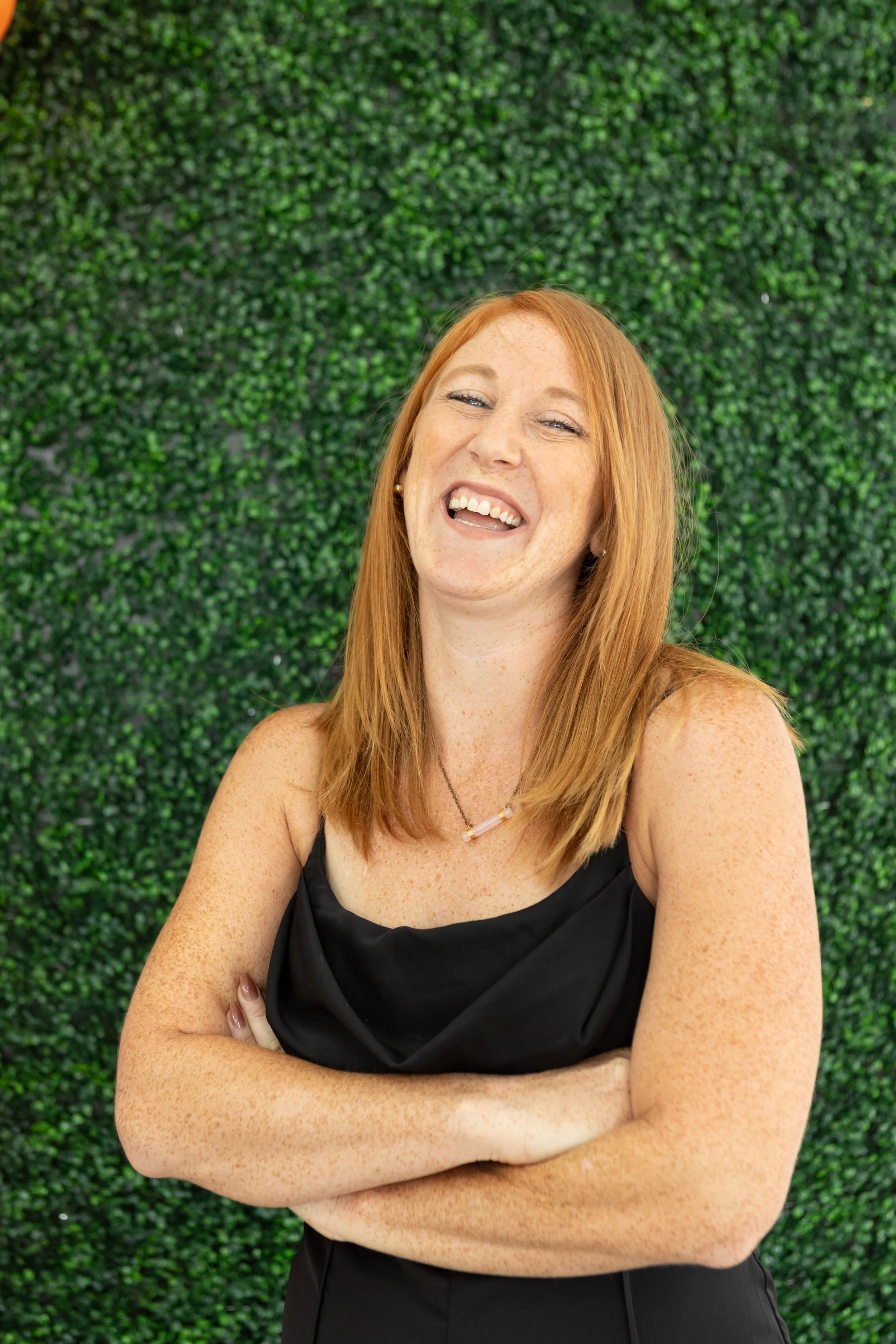 Chelsea Skaggs Columbus OH couple's postpartum coach with red hair laughing in front of a green leafy wall.