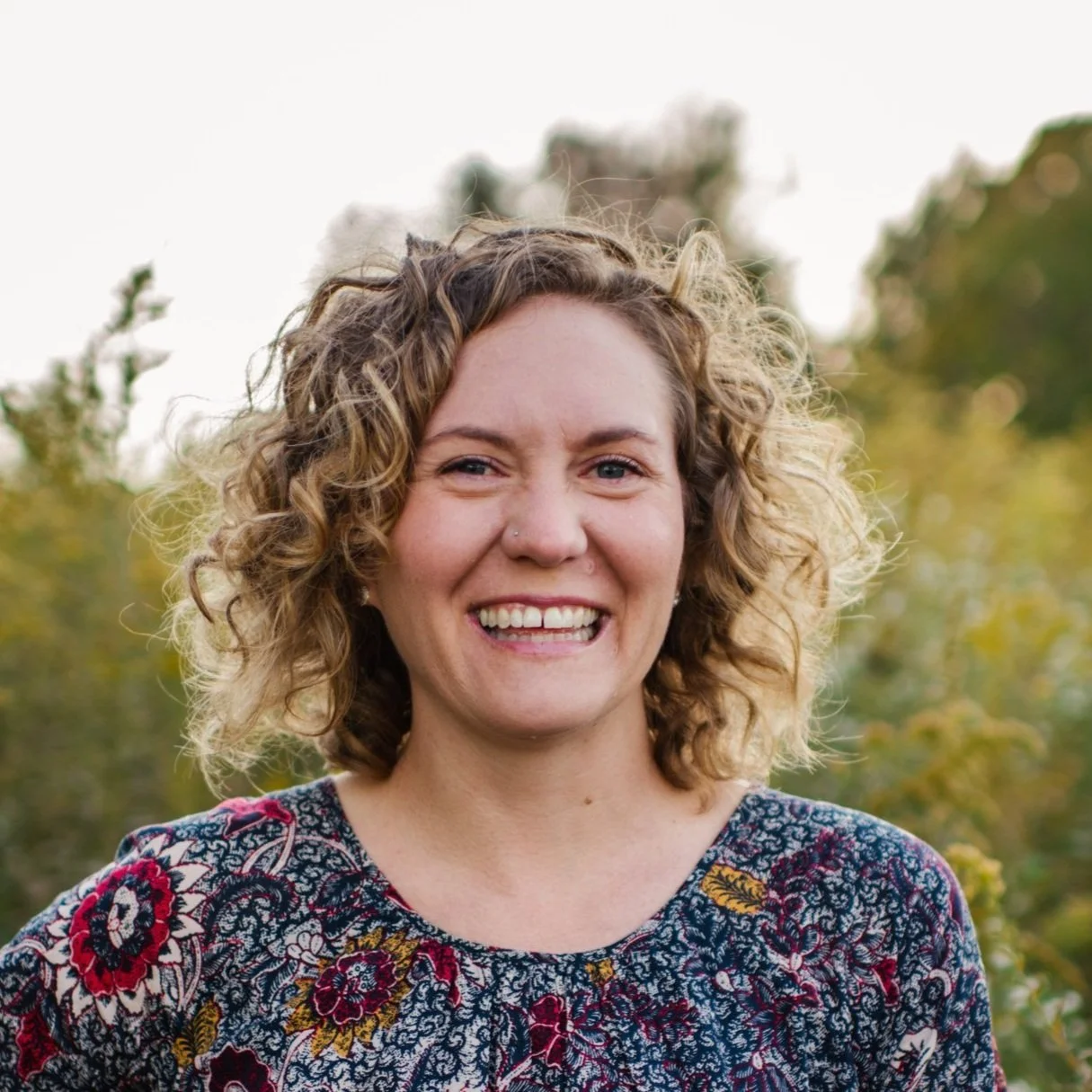Sarah Highland Columbus, OH Pelvic Floor Therapist outdoors with curly hair and floral top