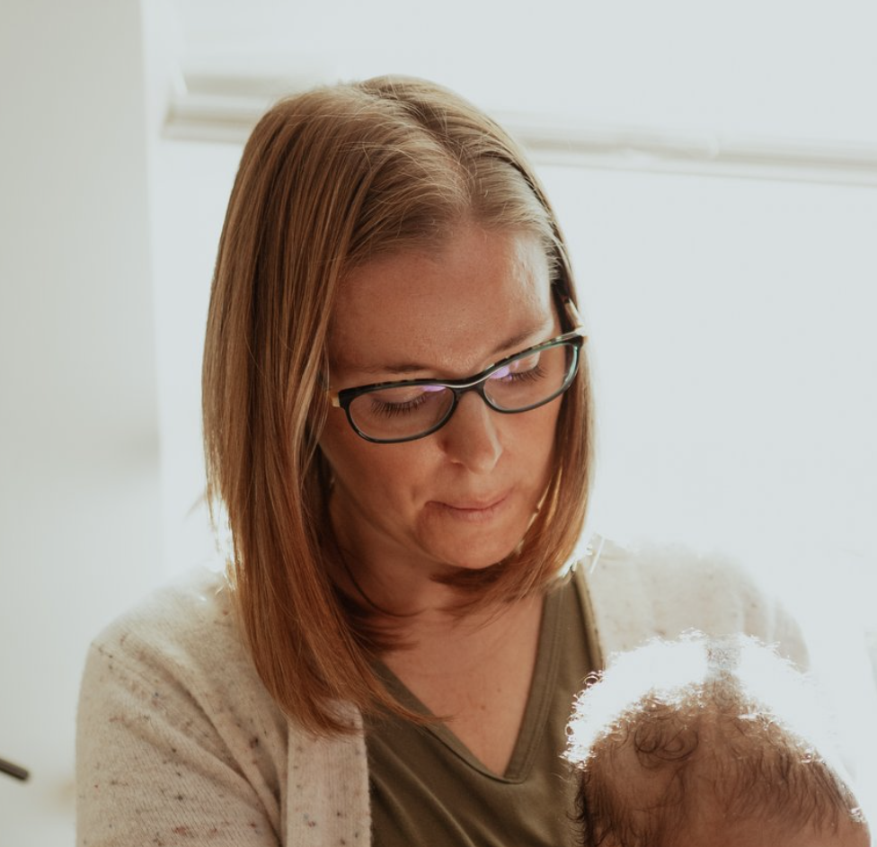 Megan Houle Little Dove Lactation IBCLC with glasses holding a baby indoors, natural lighting.