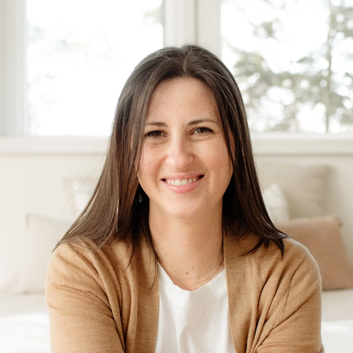 Smiling Columbus, OH Birth Doula & Childbirth Educator Erin McCaffery Crespo with long brown hair wearing a beige cardigan.