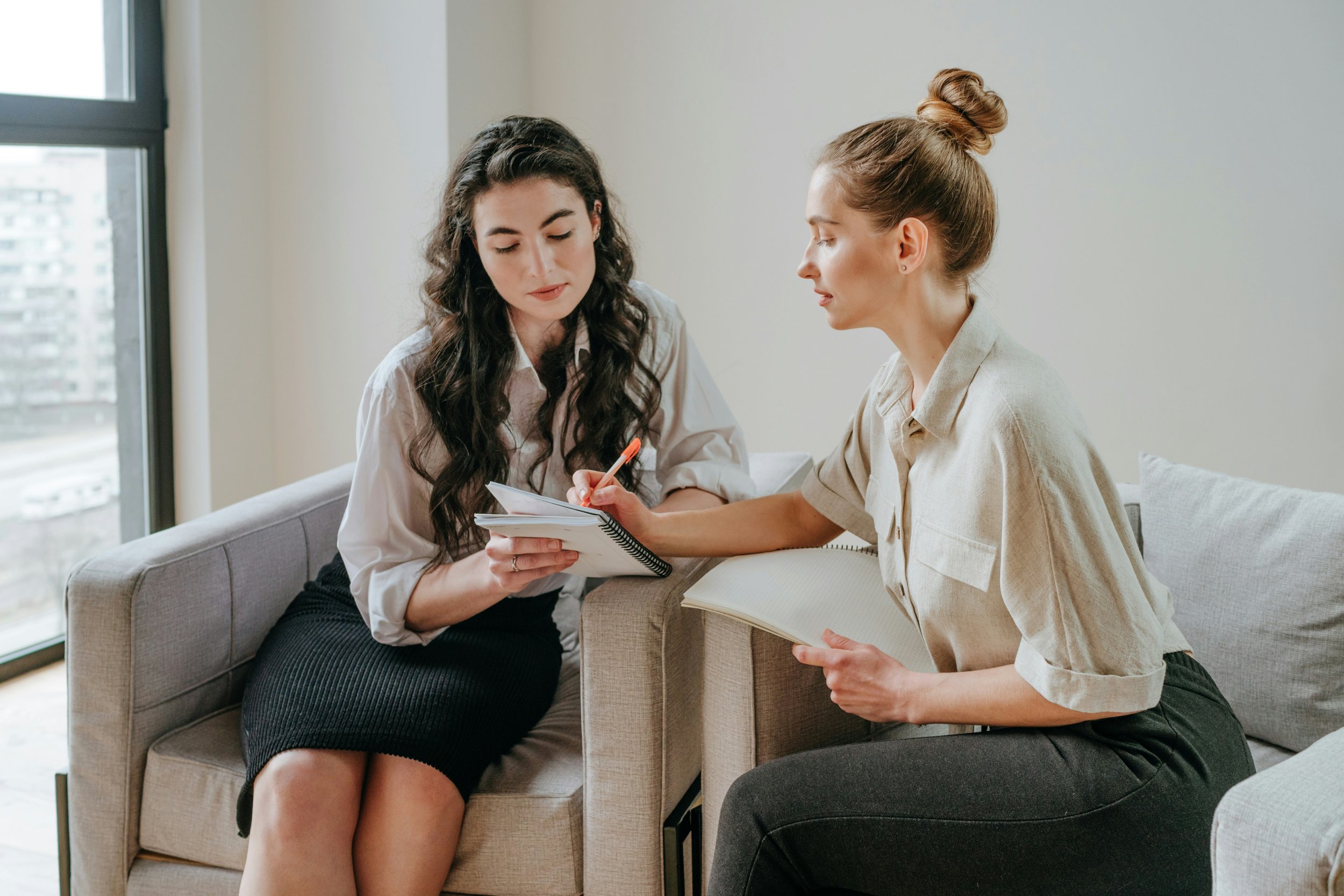 Early-career professional speaking with a more experienced colleague, representing mentorship and clinical supervision for developing therapists.