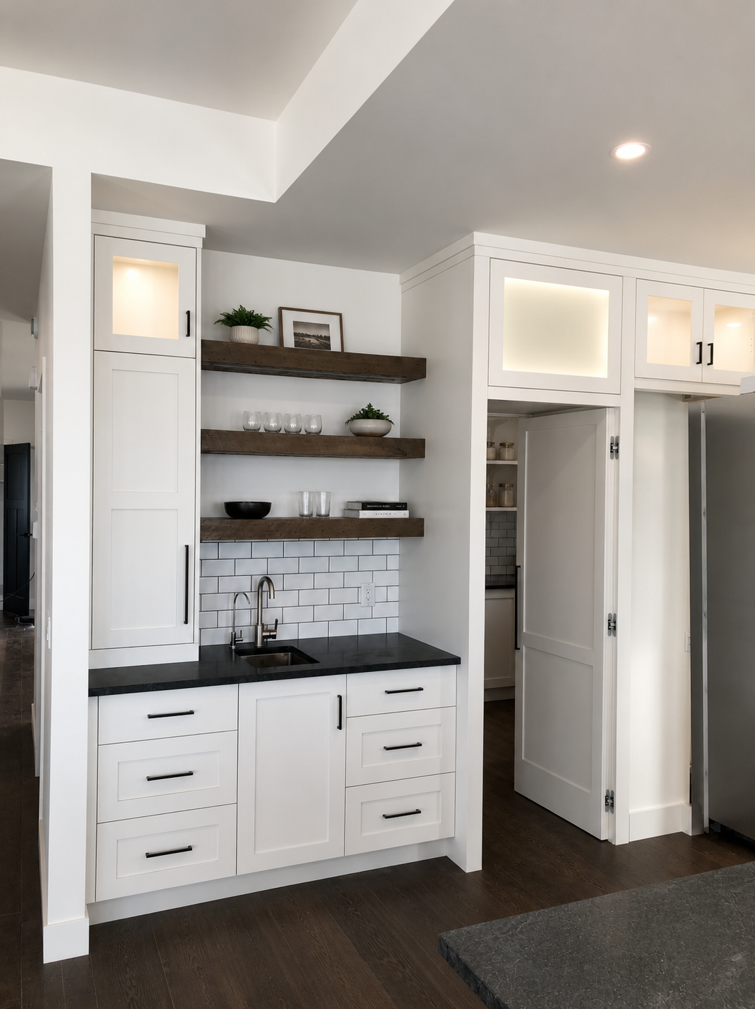 Custom white cabinetry with open wood shelving, black countertops and built-in storage by Winters Woodworks.