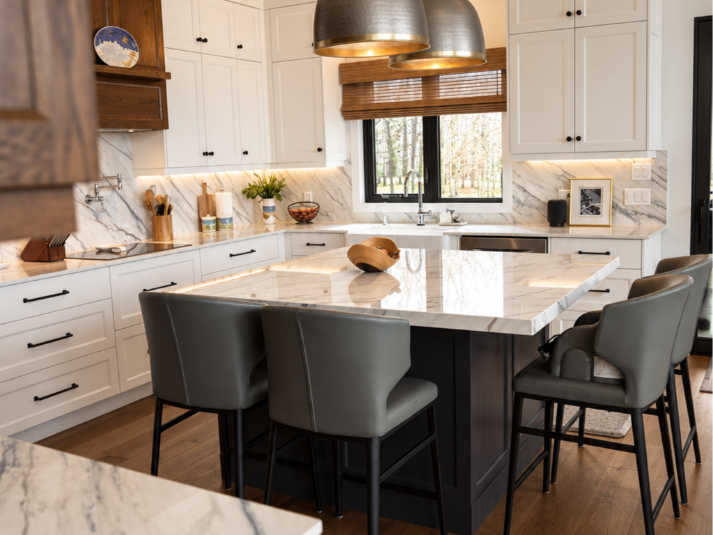 White custom cabinetry, stained wood range hood and large stone island in a Water Valley kitchen by Winters Woodworks.