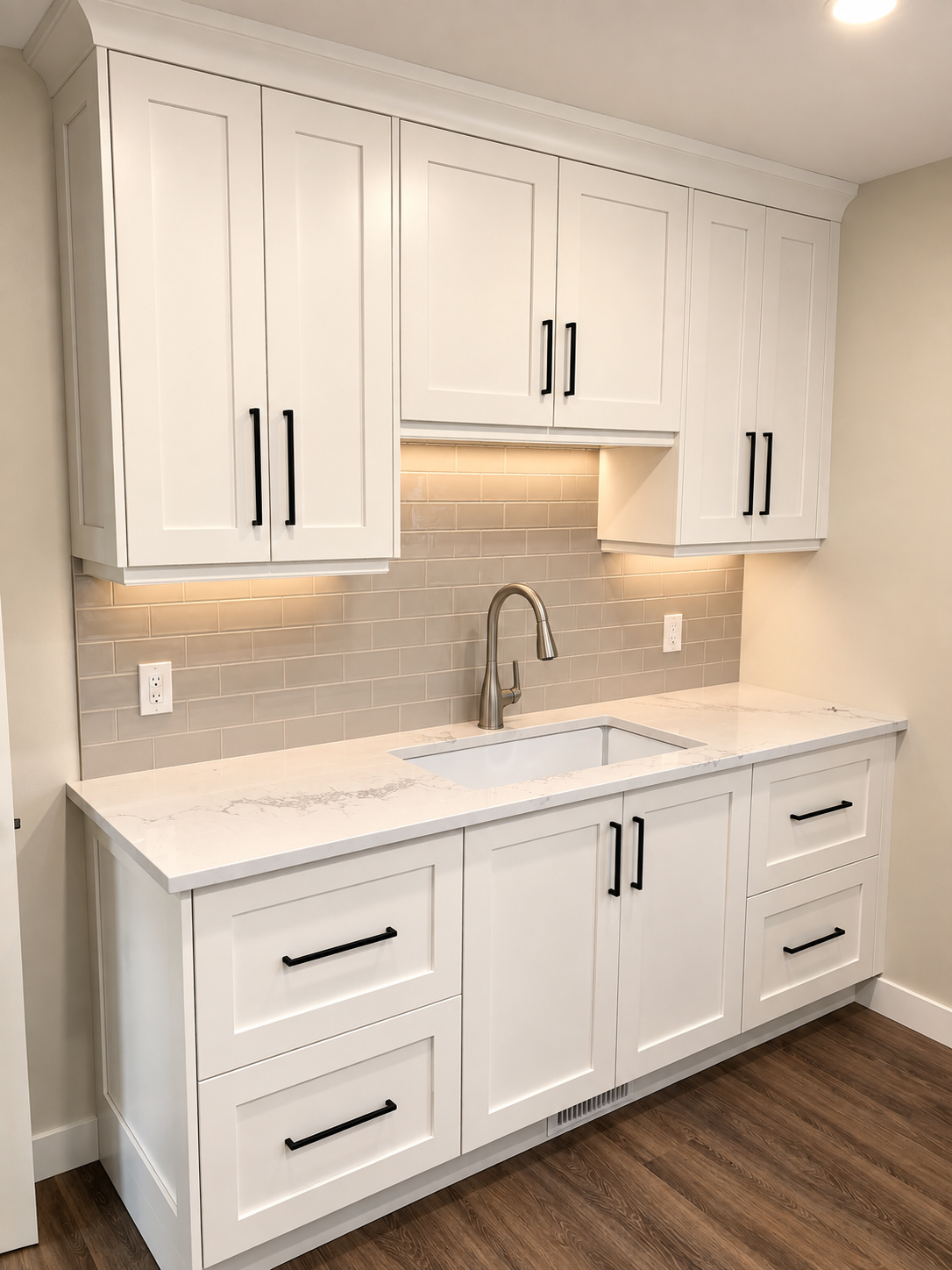 Custom white cabinetry with black hardware, stone countertops and built-in sink storage.