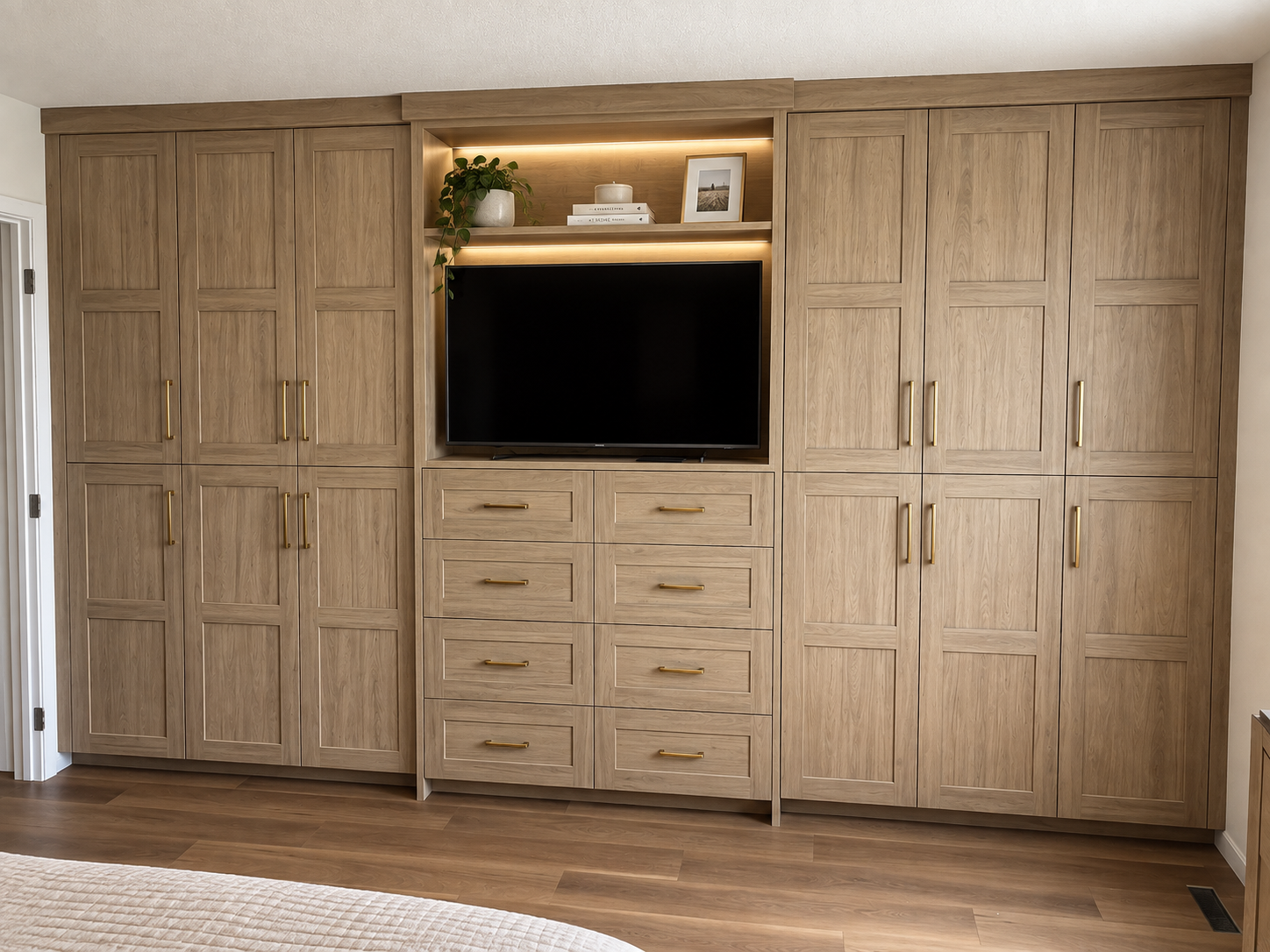 Custom floor-to-ceiling wood cabinetry with integrated TV space, drawer storage and brass hardware.