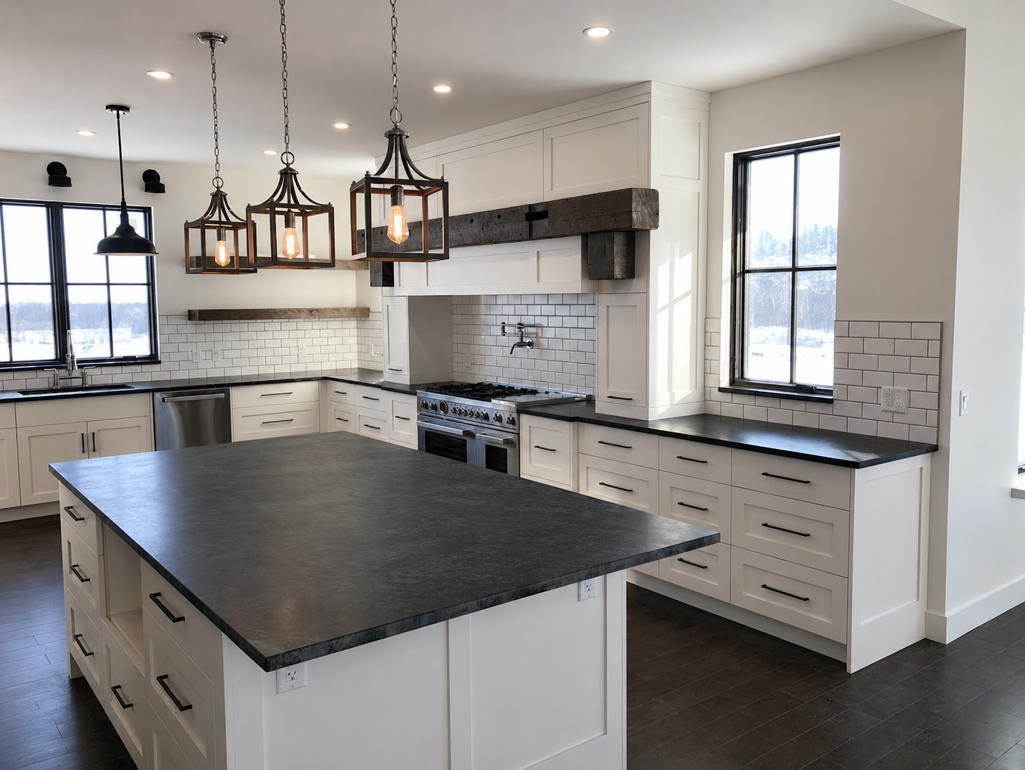 Custom white kitchen cabinetry with dark countertops, large centre island and black hardware by Winters Woodworks.