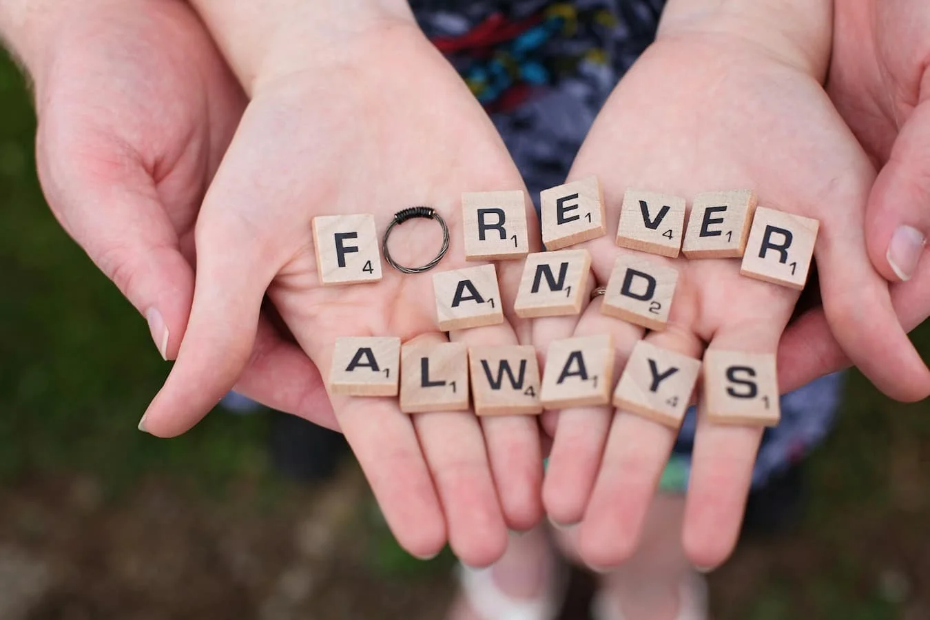 A couple's hands holding tiles saying forever and always
