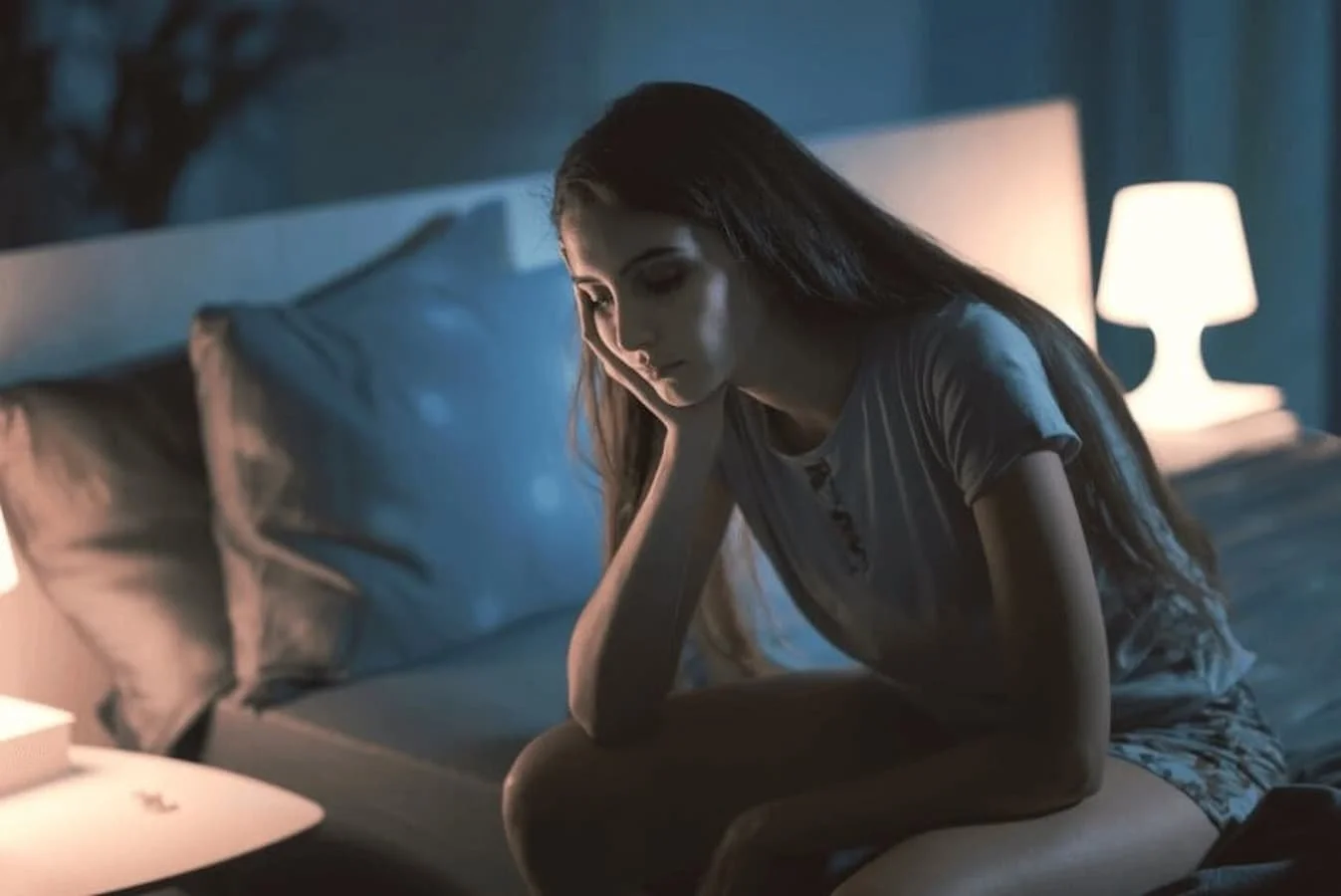 Young girl sitting in bedroom deep in thought