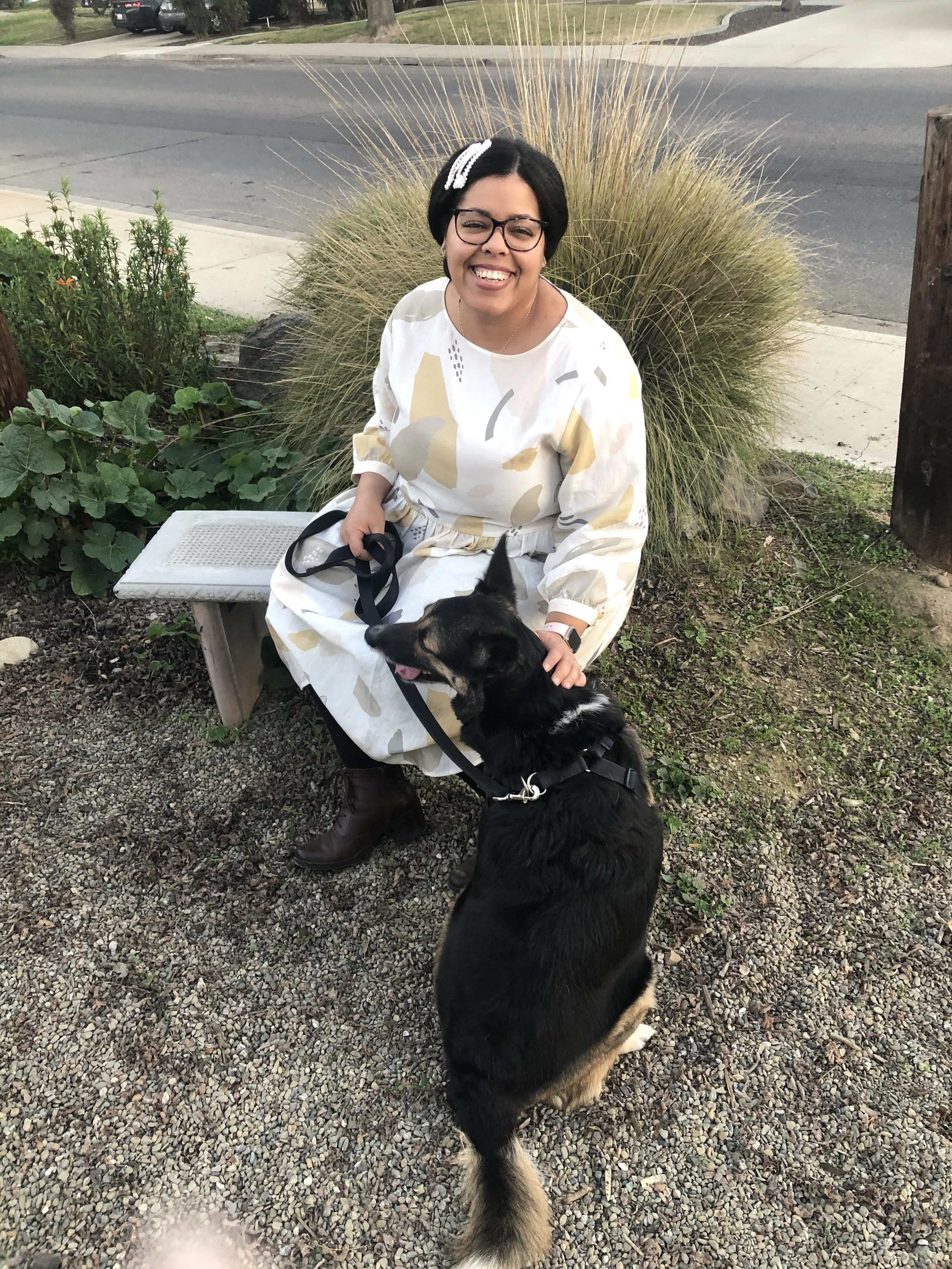 Woman sitting on bench smiling with a dog.