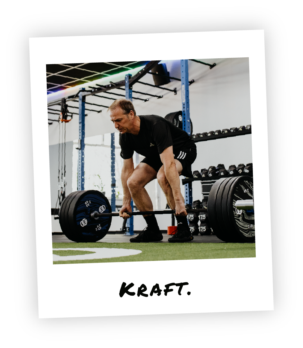 Mitglied beim Krafttraining im HM Fitness – schweres Kreuzheben mit Langhantel zur Steigerung von Muskelkraft und Stabilität im Stil eines Polaroid-Fotos und dem Schriftzug "Kraft" drauf geschrieben.