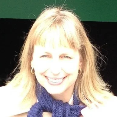 Portrait of a smiling woman with blonde hair, wearing a blue scarf and earrings, against a green and black background.