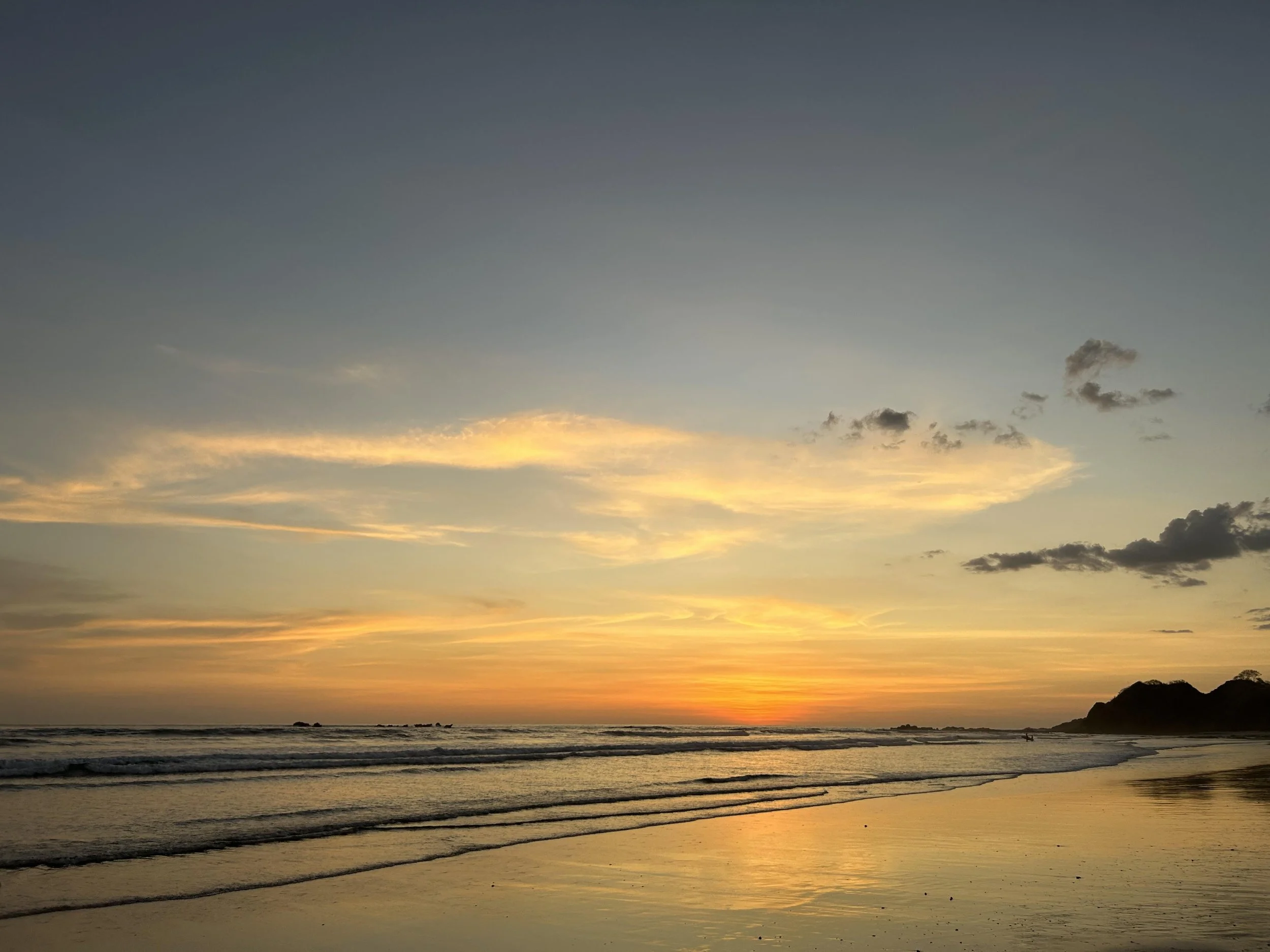 Beach sunset with calm waves and scattered clouds