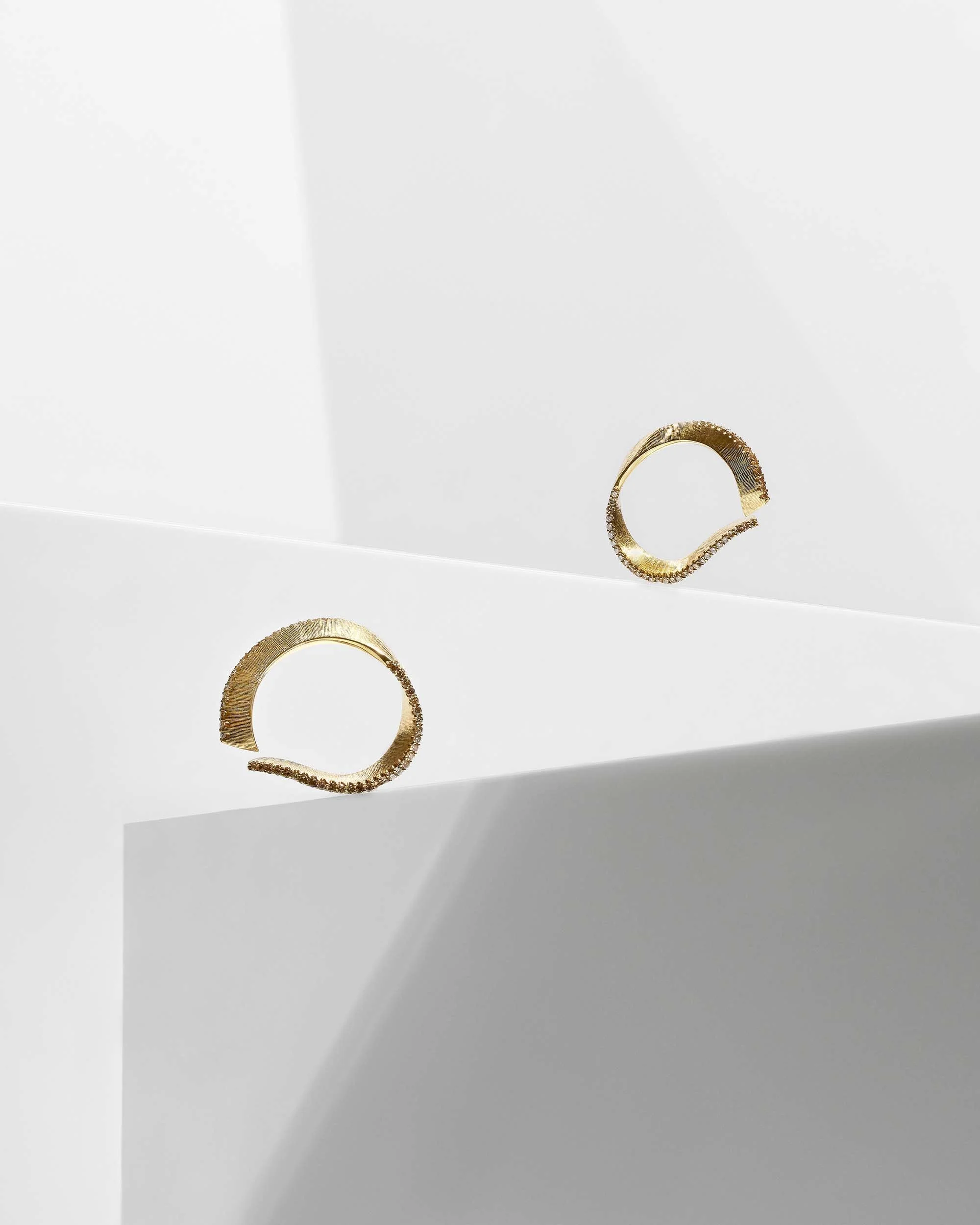 Liv Luttrell Twist diamond hoop earrings. Yellow gold with natural warm-tone diamond edge, silk engraving.
