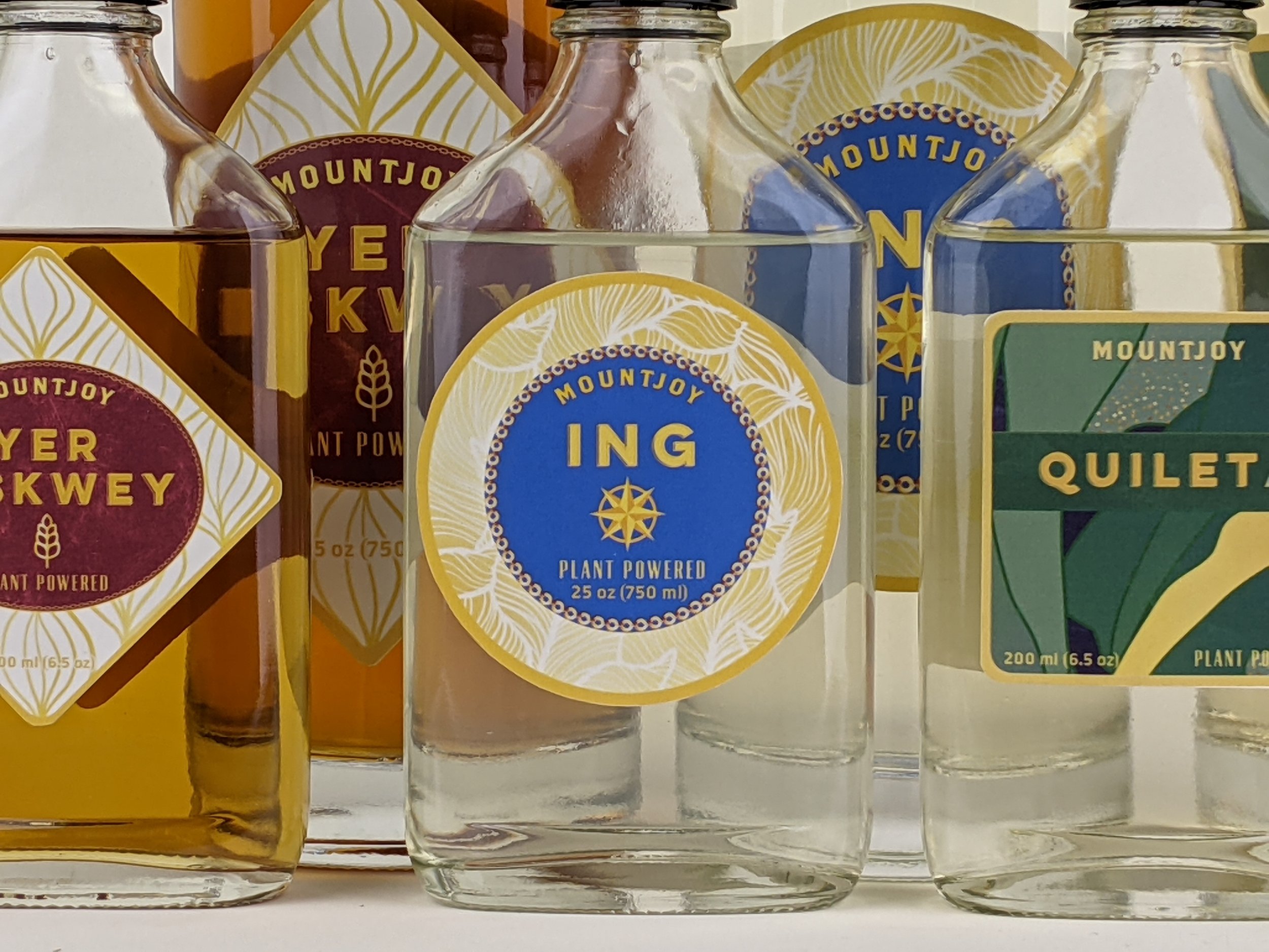 Collection of Mountjoy plant-powered beverages with colorful labels including varieties Ing, Quileta and Yer Hiskwey. 