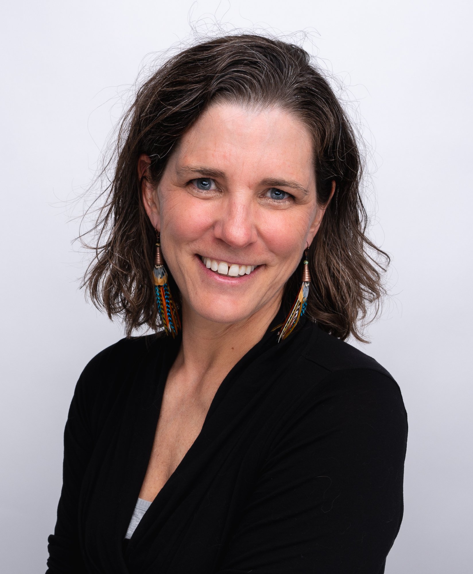 Author photo of Andie Holman wearing a black shirt and giving the camera a goofy yet sweet smile.