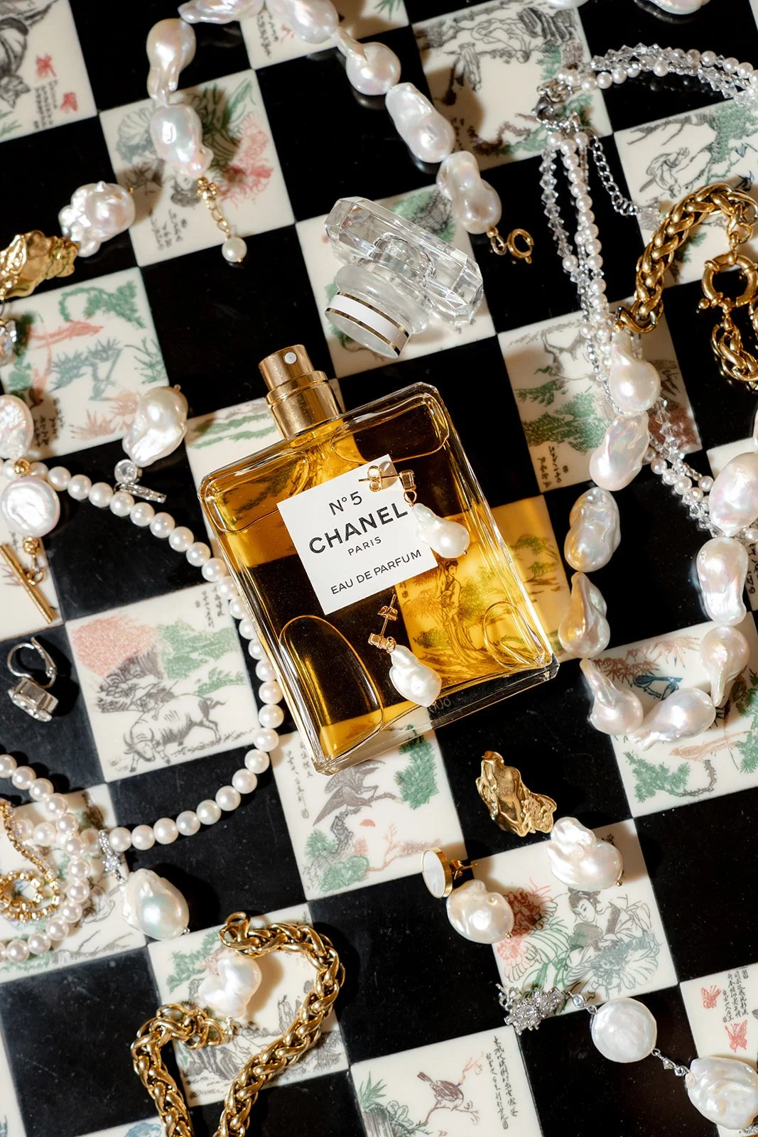 Une femme habillée en tenue traditionnelle élégante, portant des bijoux en or, avec des cheveux noirs et longs, regardant vers le bas.