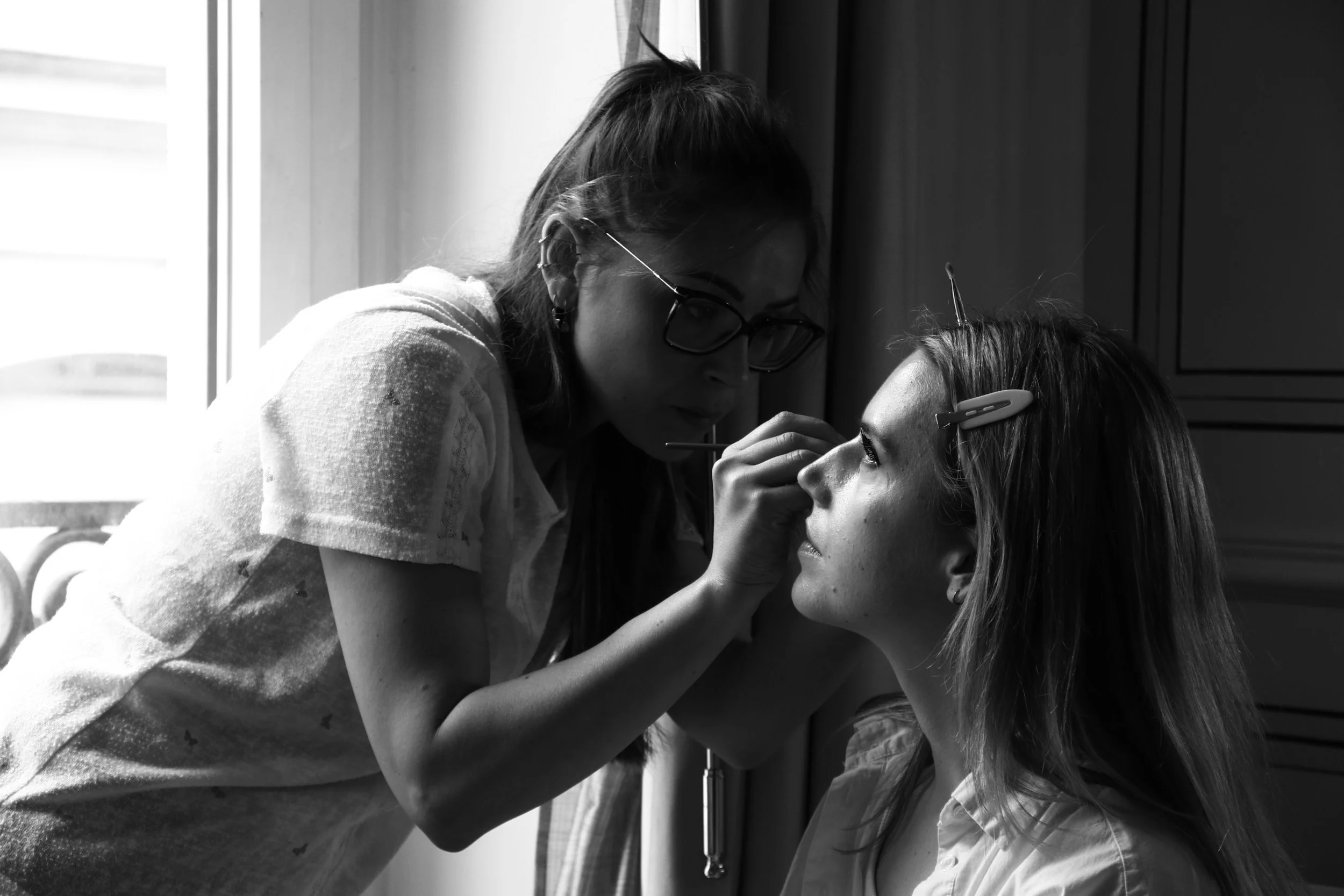 Une femme qui se fait maquiller par un professionnel dans un intérieur.