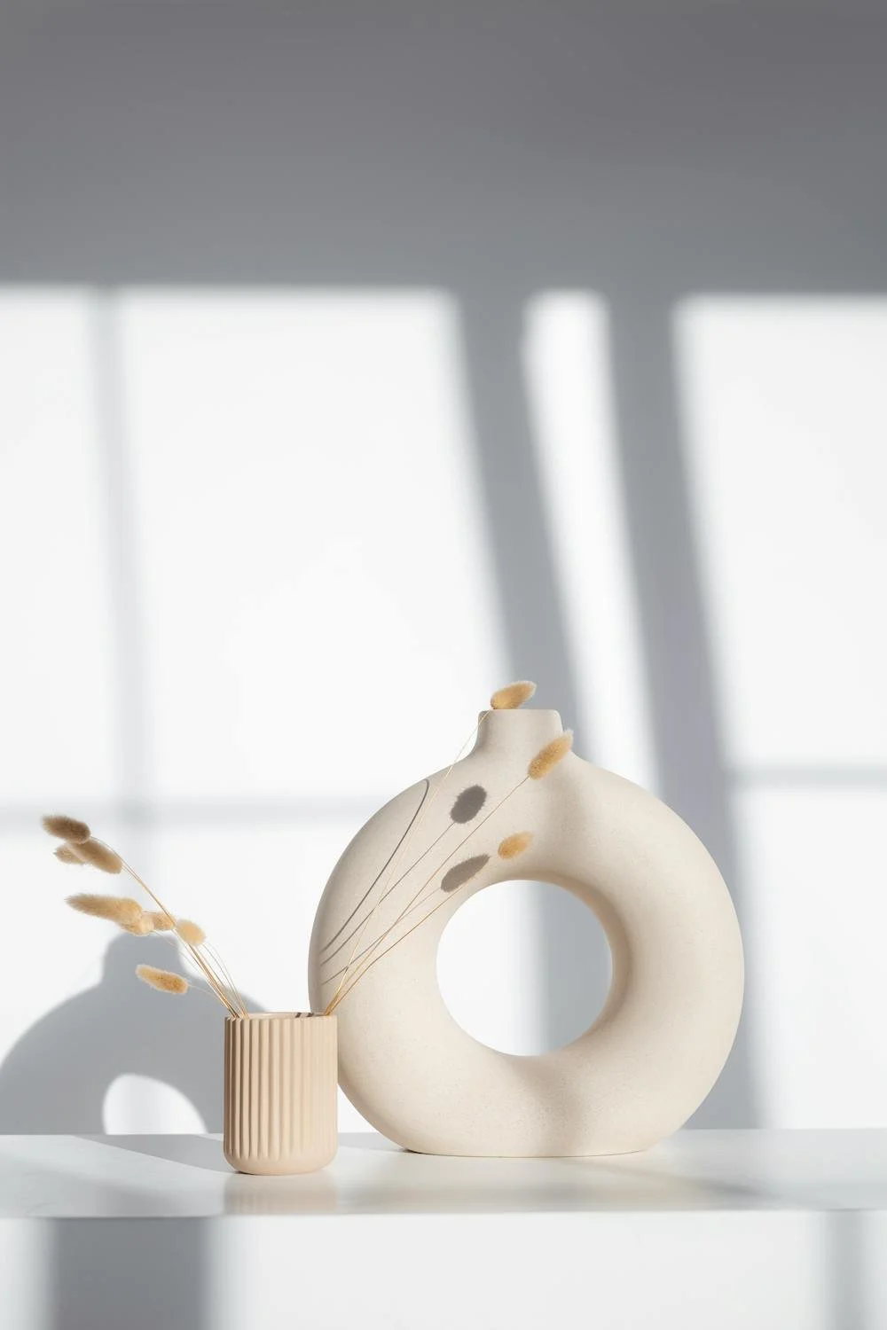 Stylish vases against a white wall with shadows from window light
