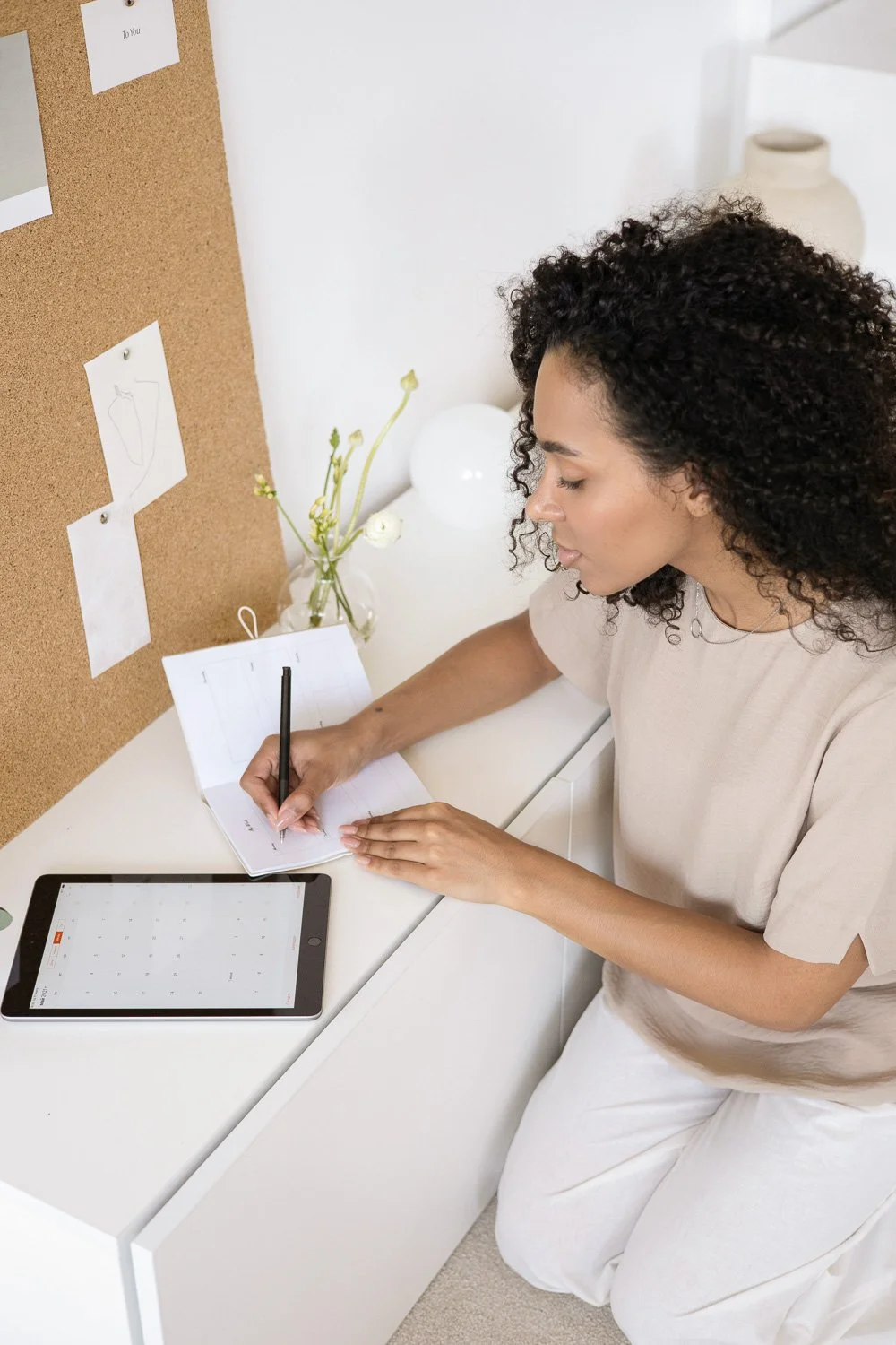 Photoshoot example: woman writing in notebook with pin board behind