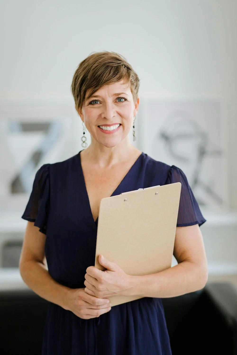 Woman holding a clip board, wearing a navy blue dress