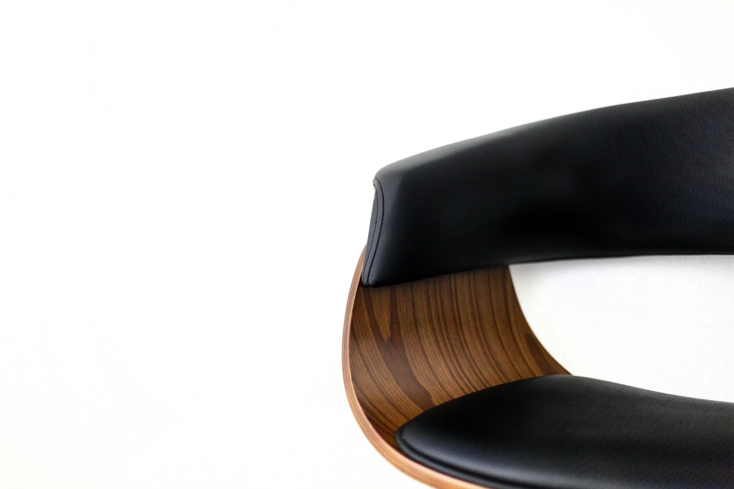 Close-up of a modern chair with black cushioned seat and backrest, and wooden armrests with a smooth curve, against a plain white background.