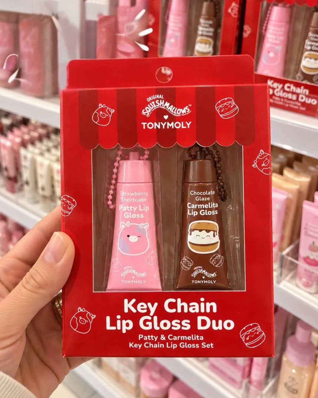 Hand holding TONYMOLY x Squishmallows key chain lip gloss duo with Patty and Carmelita in red retail packaging