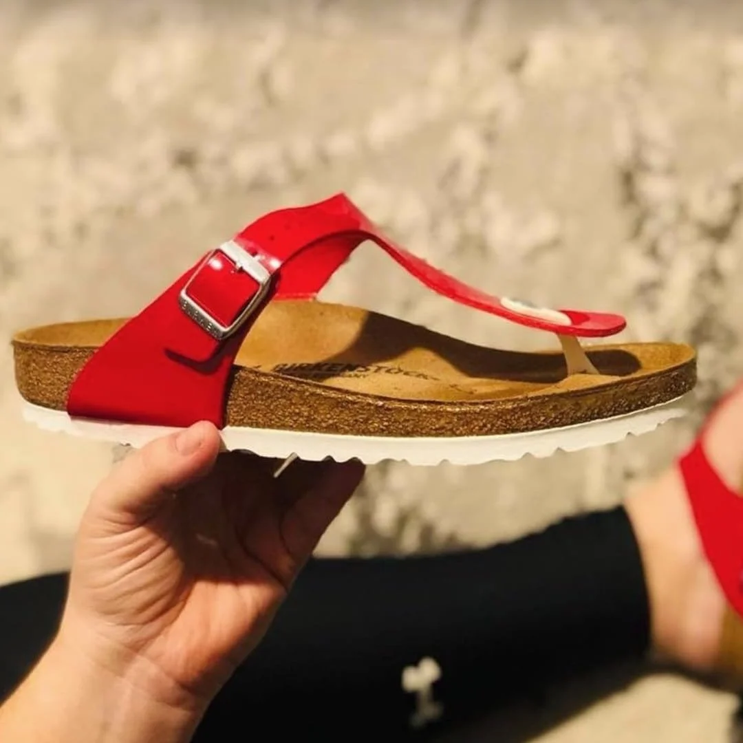 Red Birkenstock unisex thong sandal with cork footbed and white sole held outdoors