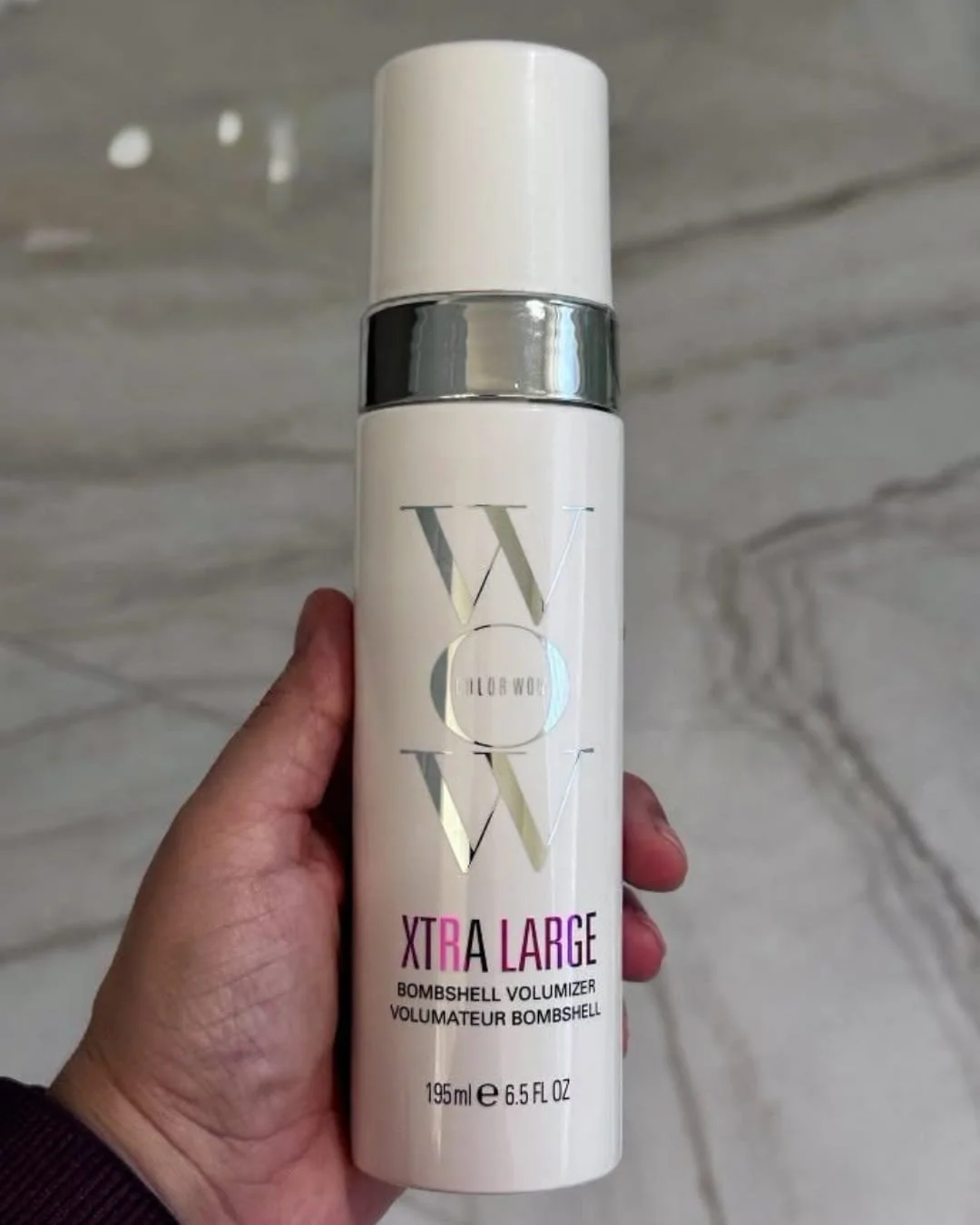 Bottle of COLOR WOW Xtra Large Bombshell Volumizer with white packaging and silver accents held against a neutral background