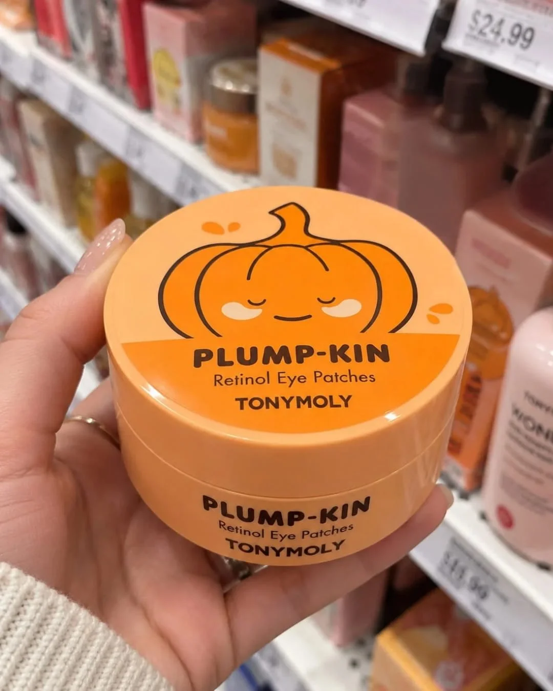 Hand holding TONYMOLY Plump-kin Retinol Eye Patches jar with cute pumpkin packaging in a retail store