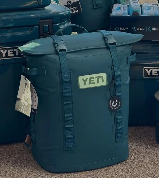 YETI backpack cooler with tags, surrounded by hard-sided coolers and ice packs.