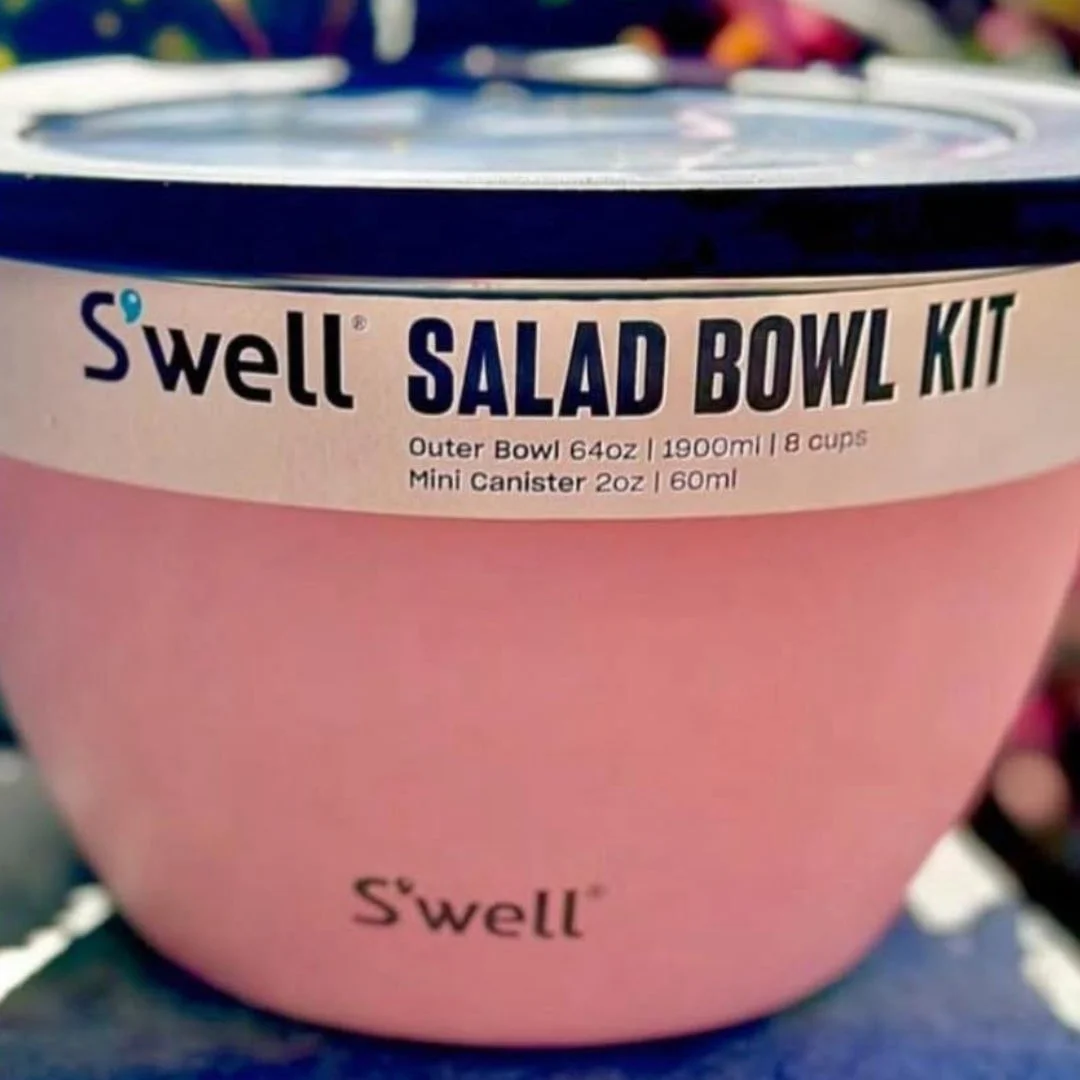 Light pink S'well Salad Bowl Kit with a 64oz capacity, featuring a sleek design, dark rim, and clear lid, ideal for carrying salads and meals on the go.