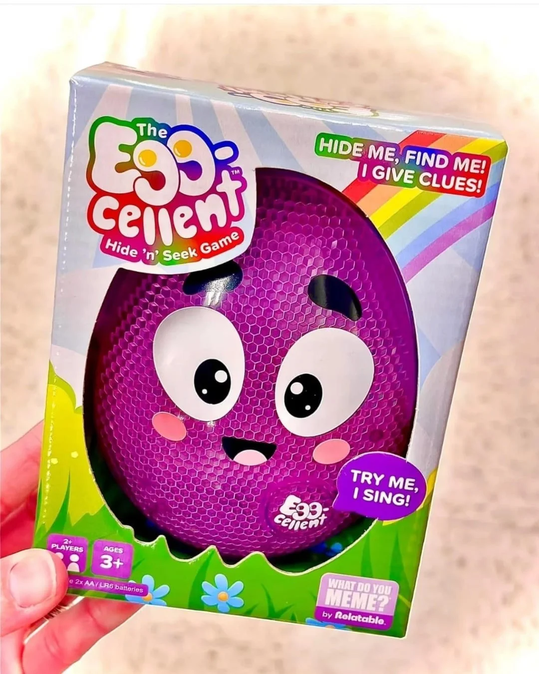Retail box for The Egg-Cellent Hide n Seek Game, featuring a cheerful purple egg-shaped character with interactive features like singing and giving clues, designed for kids aged 3 and up.