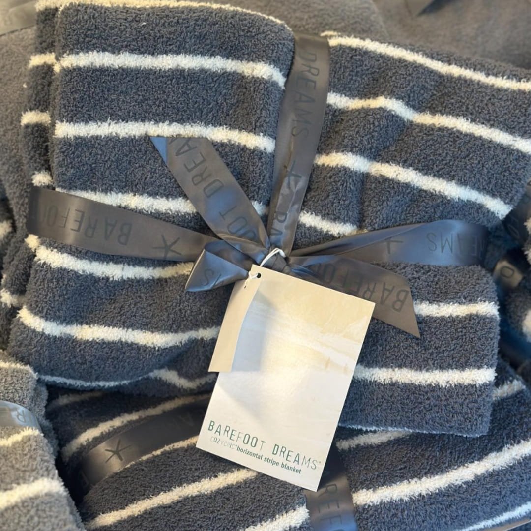 Barefoot Dreams CozyChic double stripe throw blanket in charcoal grey with white horizontal stripes, tied with branded ribbon and hang tag, showcasing soft plush texture.