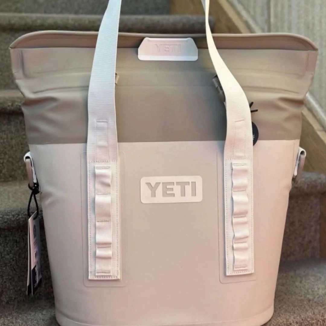 YETI Hopper soft cooler with durable white straps, featuring prominent YETI branding, displayed on a carpeted staircase.