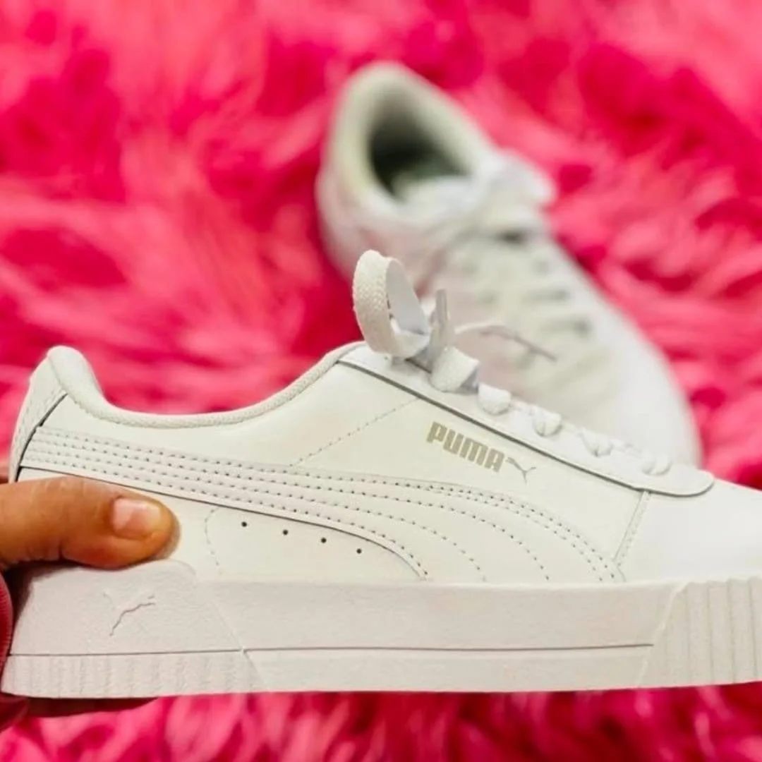 White Puma platform sneaker with gold logo displayed against bright pink textured background