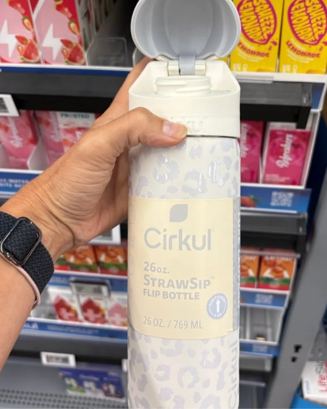 Cirkul flip water bottle with leopard print design held in store aisle in front of Cirkul flavor cartridges.