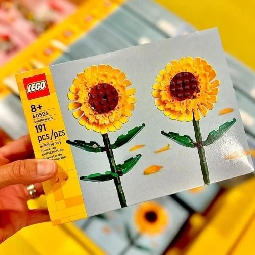 LEGO Sunflowers botanical set box with 191 pieces, age 8 and up recommendation, and a hand holding the box against a yellow retail backdrop.