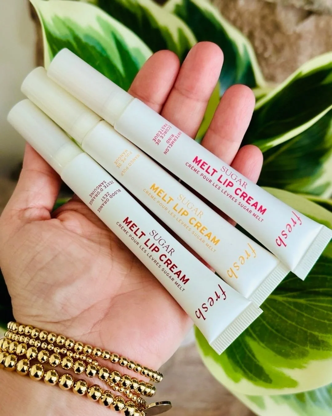 Three Sugar Melt Lip Cream tubes in watermelon, mango, and blood orange shades held in hand