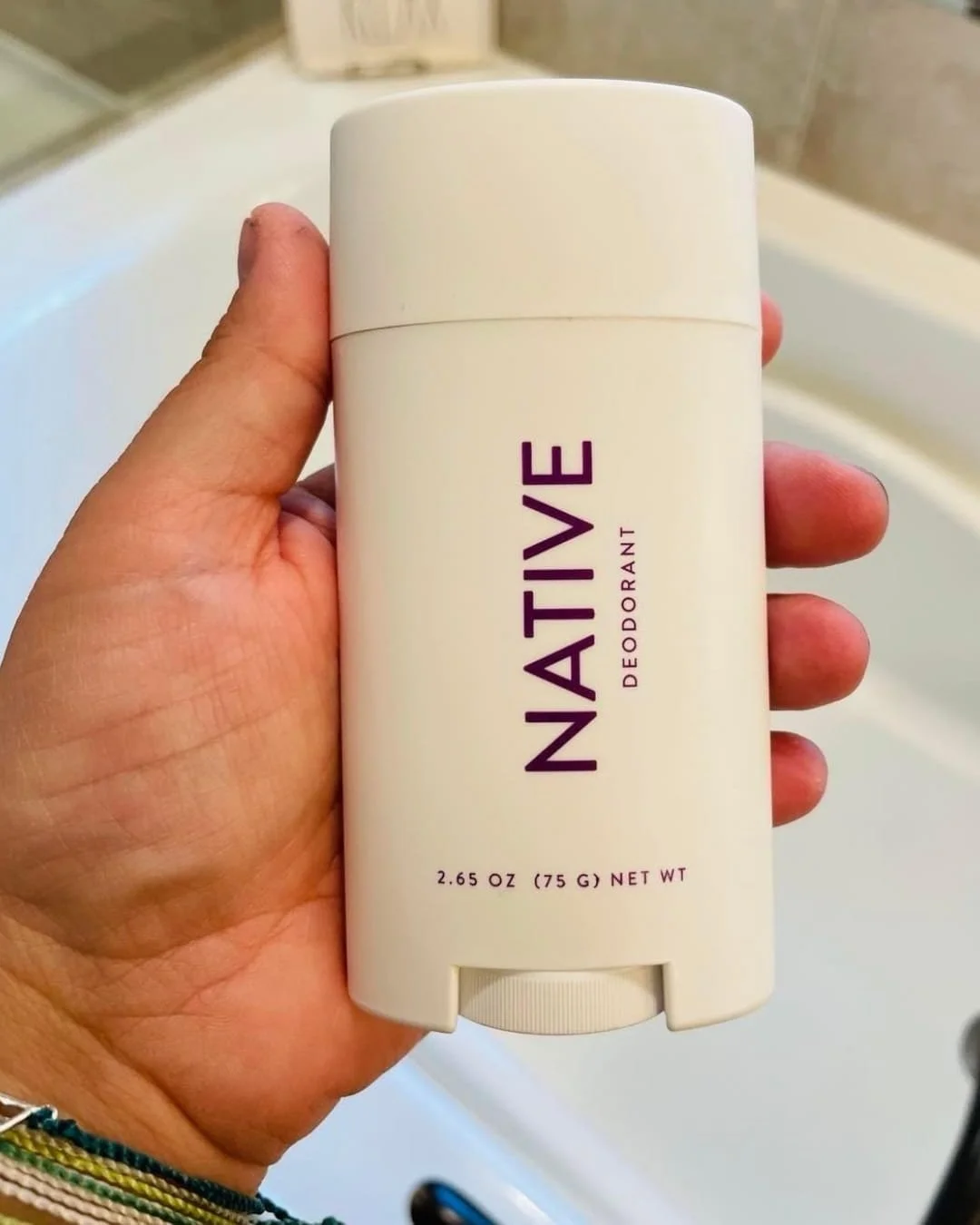 Native Odor Control deodorant stick in off-white container held in hand in bathroom.