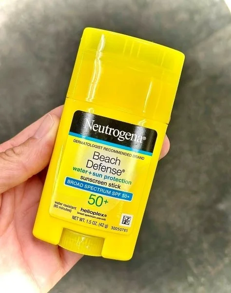 Neutrogena Beach Defense SPF 50+ sunscreen stick, water-resistant, held against a dark background.