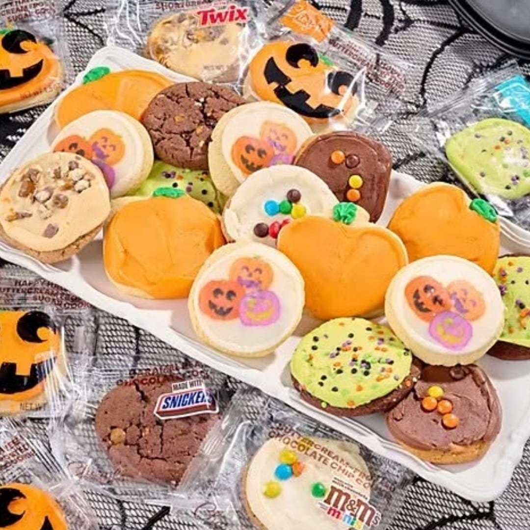 Halloween cookie platter with pumpkin-shaped sugar cookies, jack-o'-lantern designs, frosted treats, and individually wrapped candy-inspired cookies