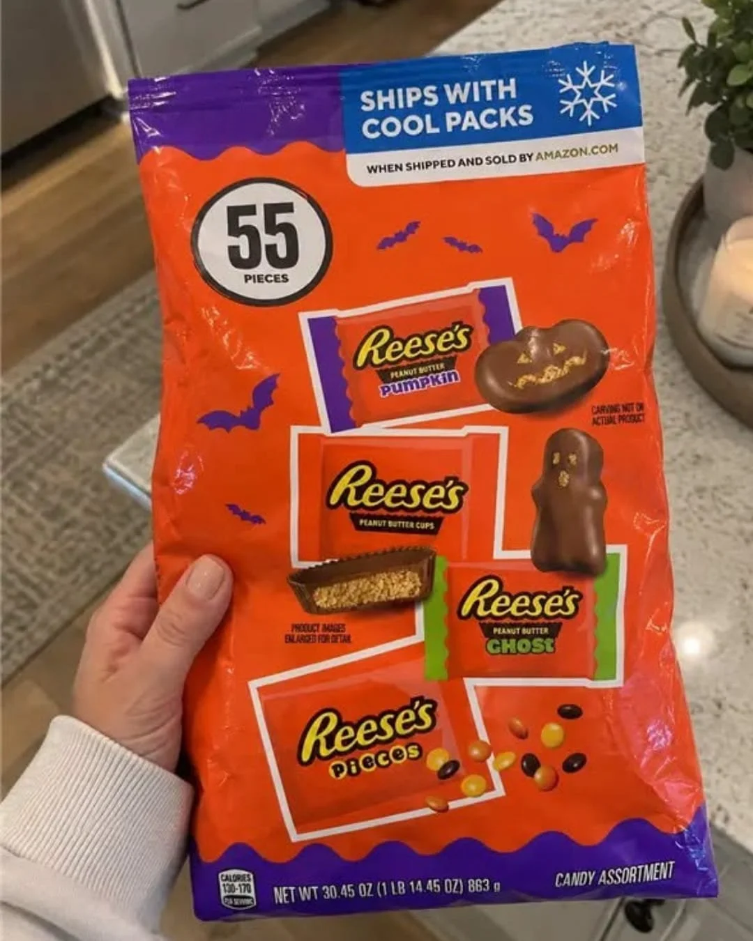 Hand holding a Reese’s Halloween candy assortment bag with peanut butter pumpkins, cups, ghosts, and Reese’s Pieces