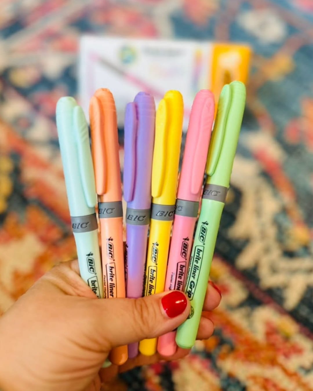 Hand holding a set of six BIC pastel highlighters in blue, peach, purple, yellow, pink, and green
