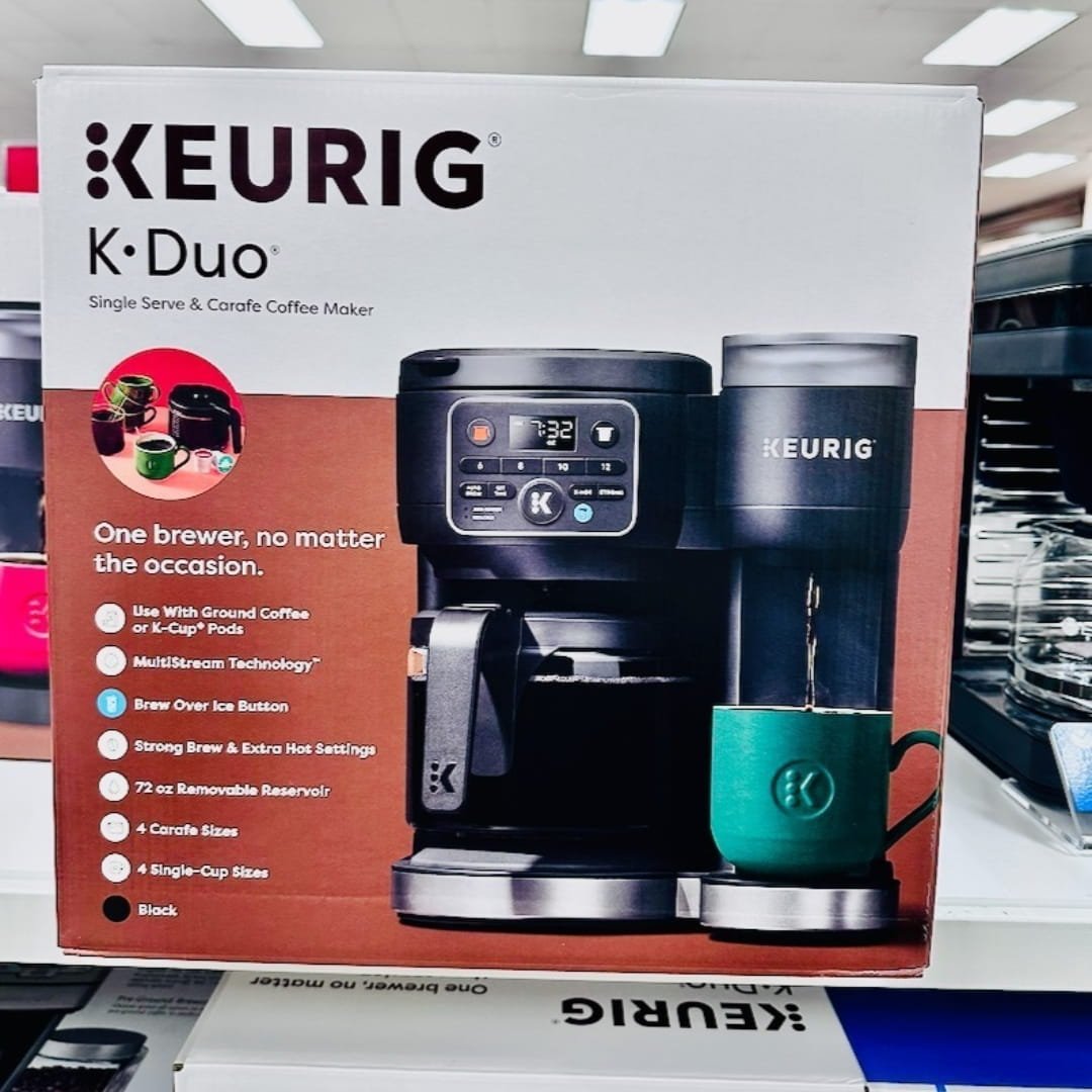 Keurig K-Duo coffee maker retail box showcasing a black machine with a carafe on one side and a single-serve brewer on the other, featuring highlights like MultiStream Technology, Brew Over Ice, and compatibility with ground coffee and K-Cup pods.