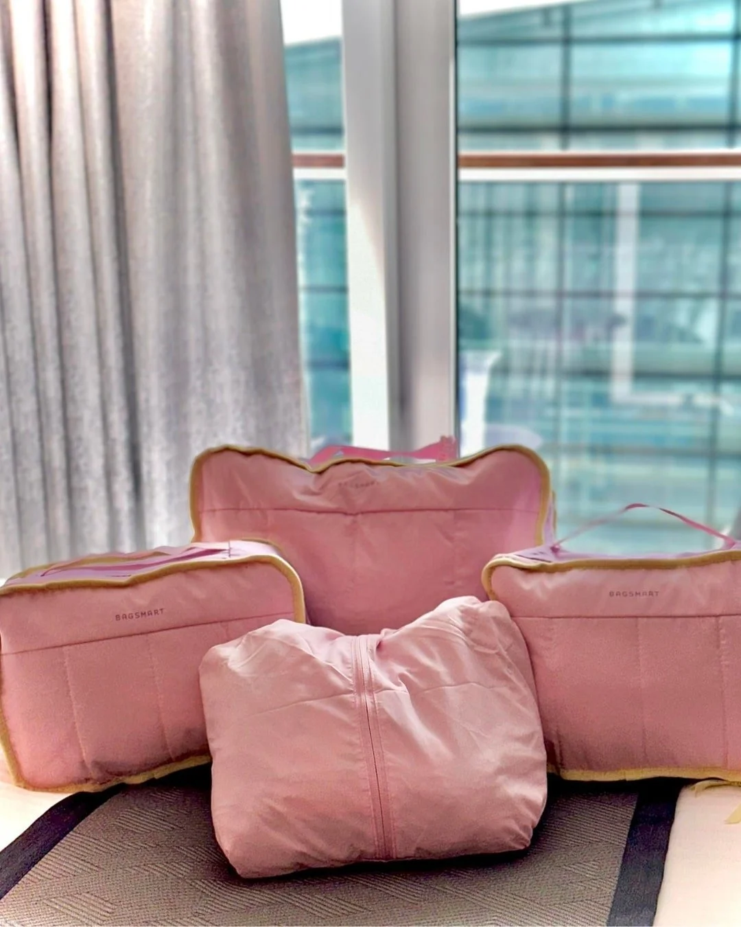 Set of four pink BAGSMART packing cubes with gold trim, perfect for travel and luggage organization.