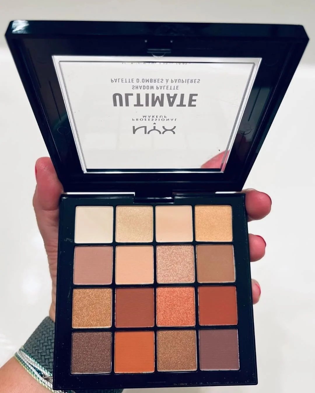 Open NYX Ultimate Shadow Palette Warm Neutrals with 16 eyeshadow shades held in hand
