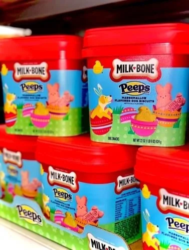 Retail display of Milk-Bone Peeps Marshmallow Flavored Dog Biscuits in red-lidded tubs with Easter-themed labels featuring Peeps bunnies, chicks, and decorated eggs.