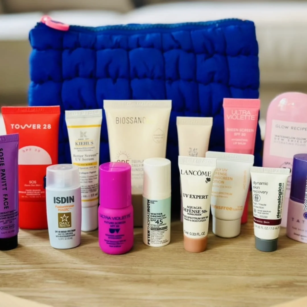 Sephora Sun Safety Kit featuring 13 travel-sized sunscreens from brands like Lancôme, Kiehl's, Glow Recipe, and Ultra Violette, arranged on a wooden surface with a bright blue quilted travel bag in the background.